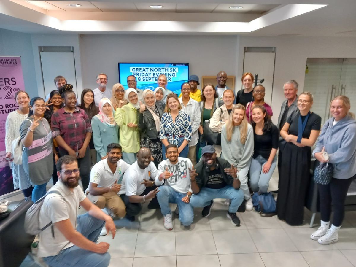 Large group of project colleagues and participants smiling together in a workshop room